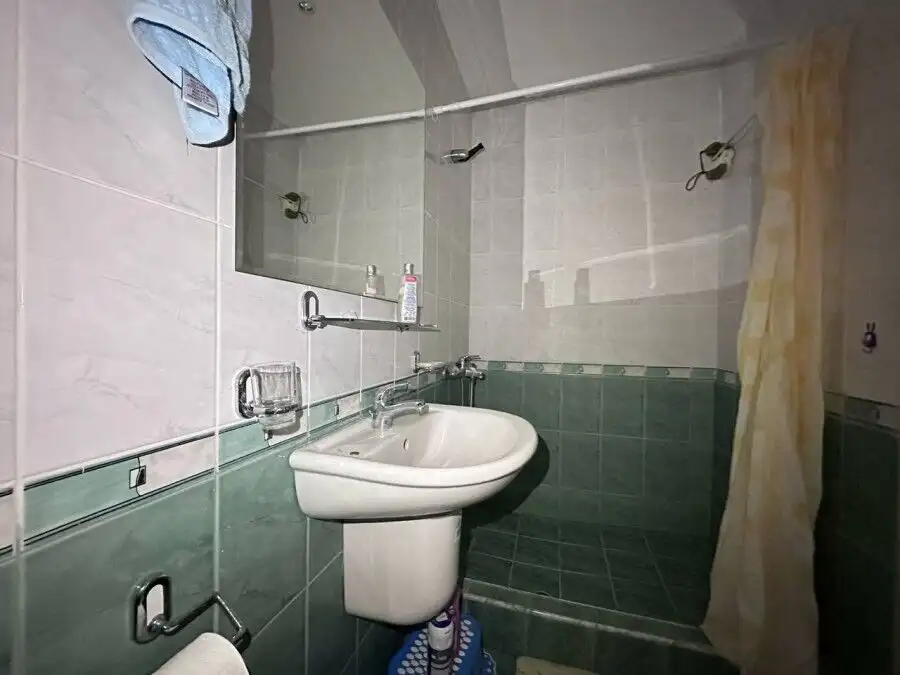 Small bathroom with sink, mirror, and shower in a sea-front apartment in Coral Beach, St. Vlas.