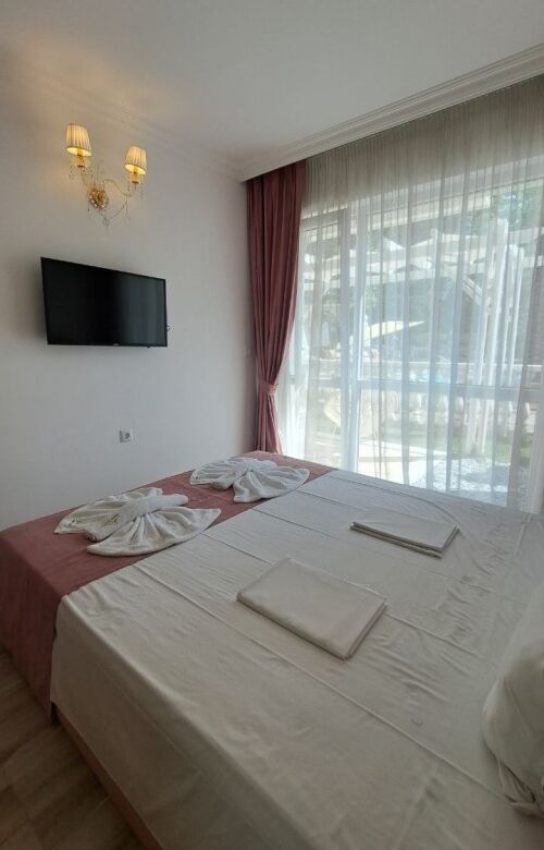 Bright bedroom with large window, elegant curtains, and modern decor in Sunny Beach apartment.