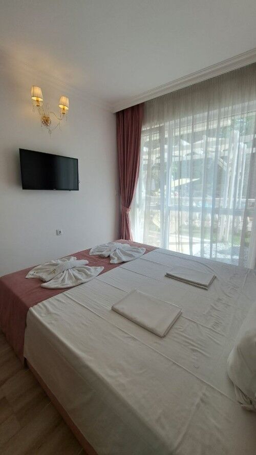 Bright bedroom with large window, elegant curtains, and modern decor in Sunny Beach apartment.