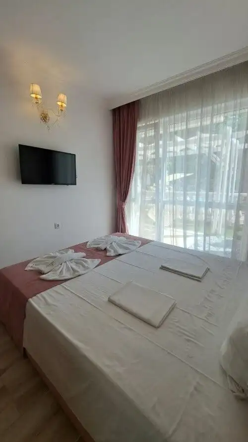 Bright bedroom with large window, elegant curtains, and modern decor in Sunny Beach apartment.