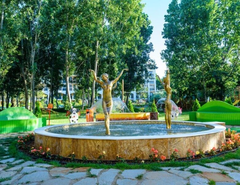Fountain with two golden statues in a lush green park at Sweet Homes 6, Sunny Beach.