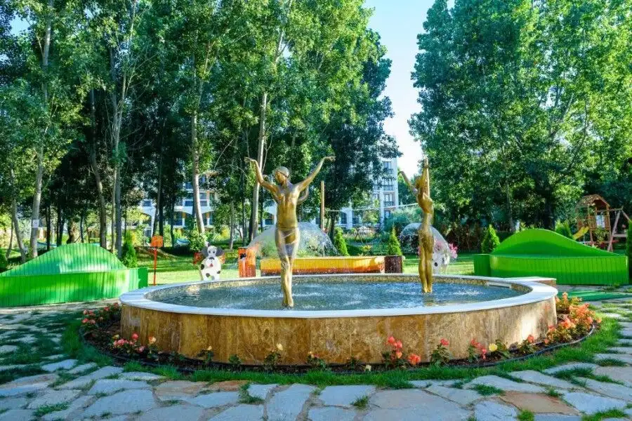 Fountain with two golden statues in a lush green park at Sweet Homes 6, Sunny Beach.