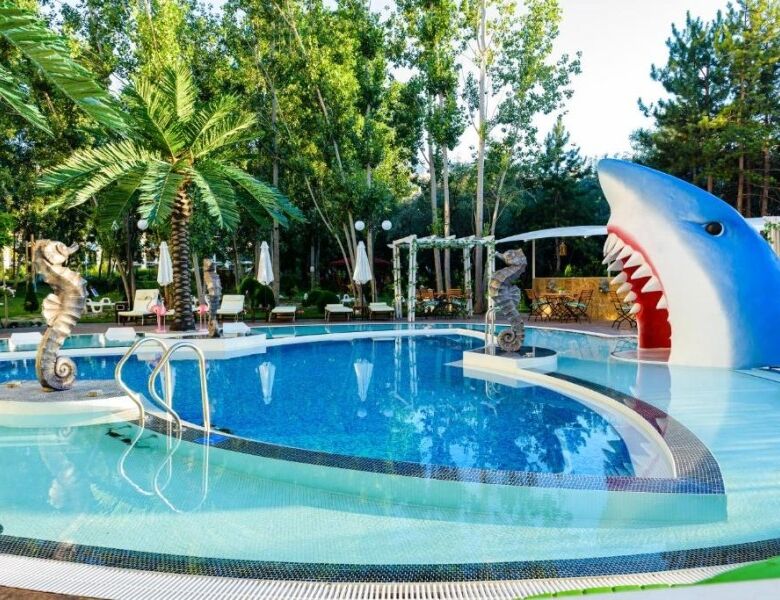 Pool area with shark-shaped slide and tropical greenery at Sweet Homes 6, Sunny Beach.