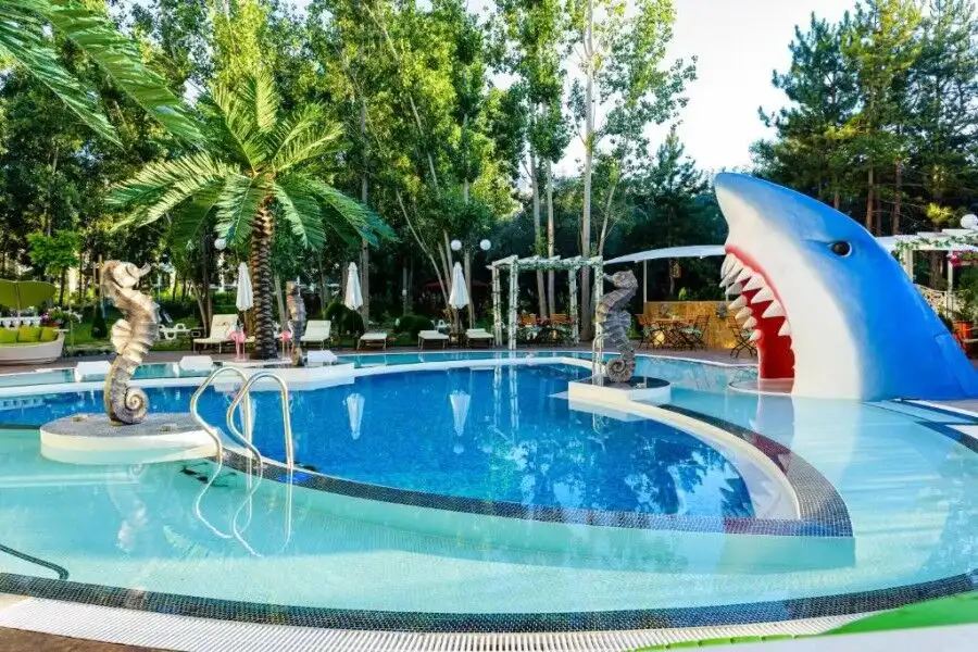 Pool area with shark-shaped slide and tropical greenery at Sweet Homes 6, Sunny Beach.