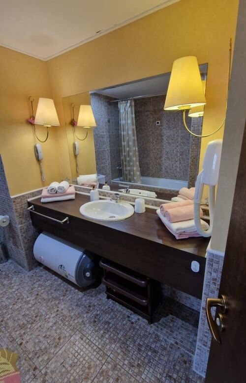 Bathroom with double sinks, warm lighting, and a view of the city skyline through the window.
