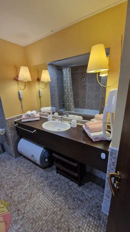 Bathroom with double sinks, warm lighting, and a view of the city skyline through the window.