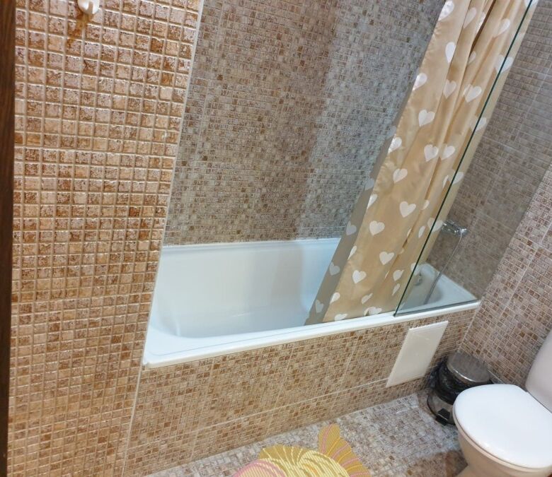 Bathroom with bathtub, shower curtain, and tiled walls for a comfortable home experience.
