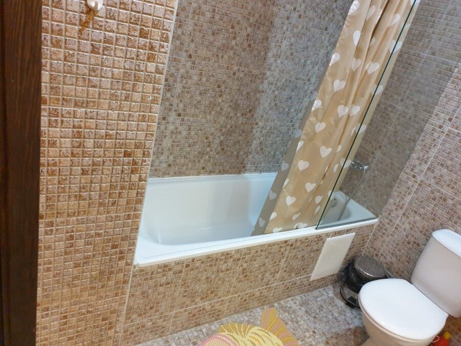 Bathroom with bathtub, shower curtain, and tiled walls for a comfortable home experience.