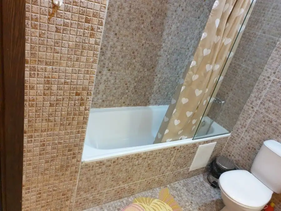 Bathroom with bathtub, shower curtain, and tiled walls for a comfortable home experience.