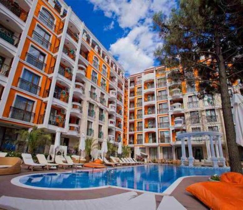 Apartment complex with pool, sun loungers, and lush surroundings in Sunny Beach.