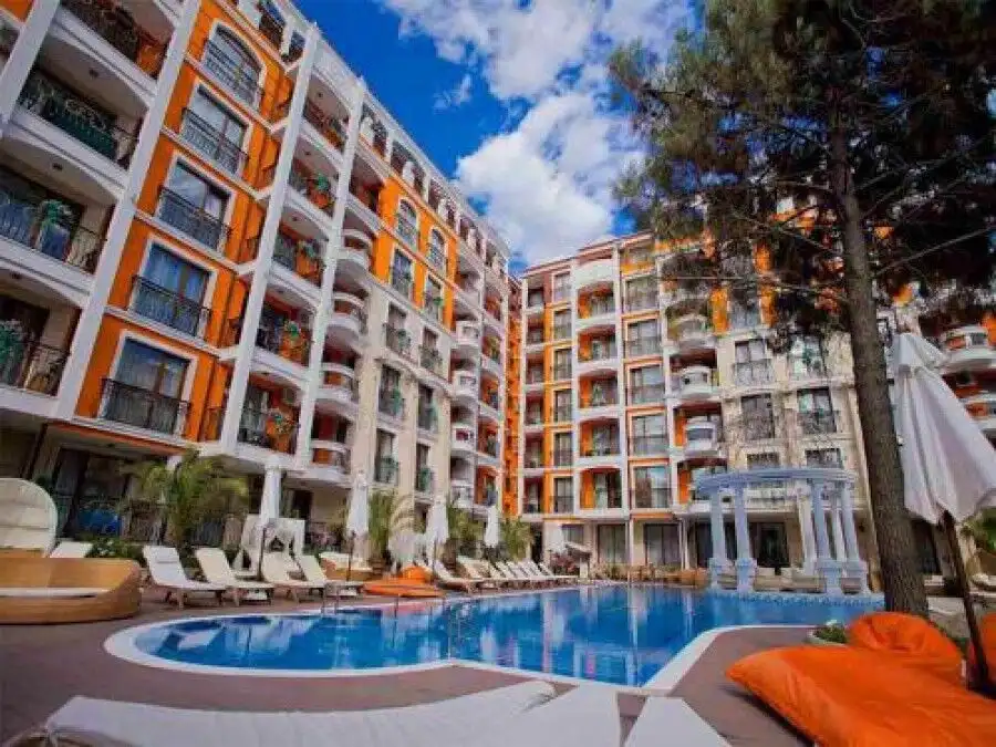 Apartment complex with pool, sun loungers, and lush surroundings in Sunny Beach.