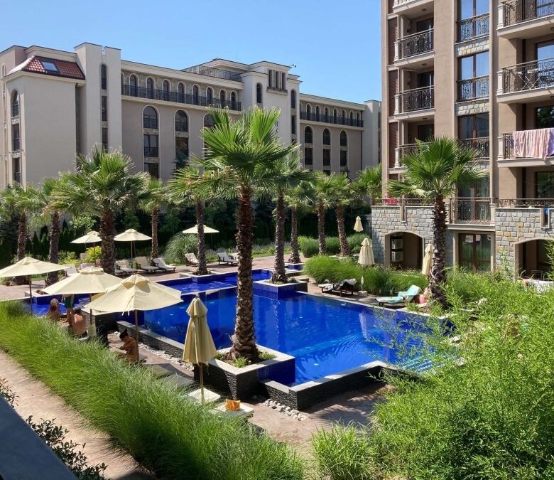 Bright poolside apartment with lush greenery and palm trees at Cascadas Family Resort, Sunny Beach.