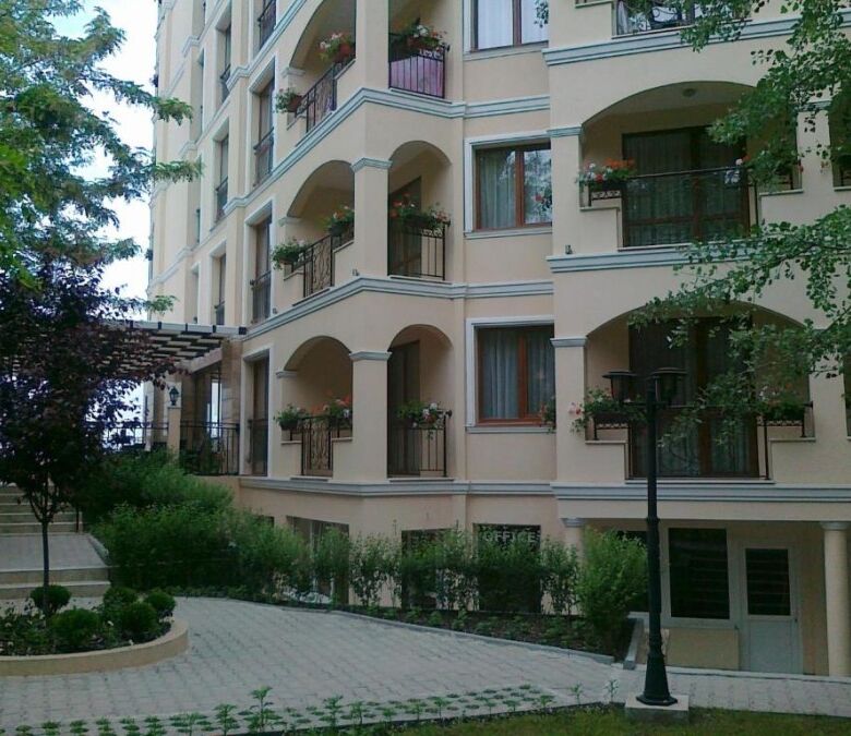 Apartment building with balconies and greenery in Sunny Beach, close to the beach.