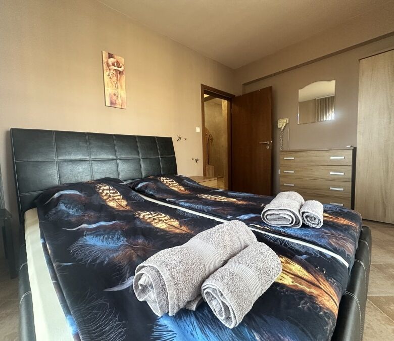 Comfortable bedroom with two beds, towels, and mountain scenery in the background.