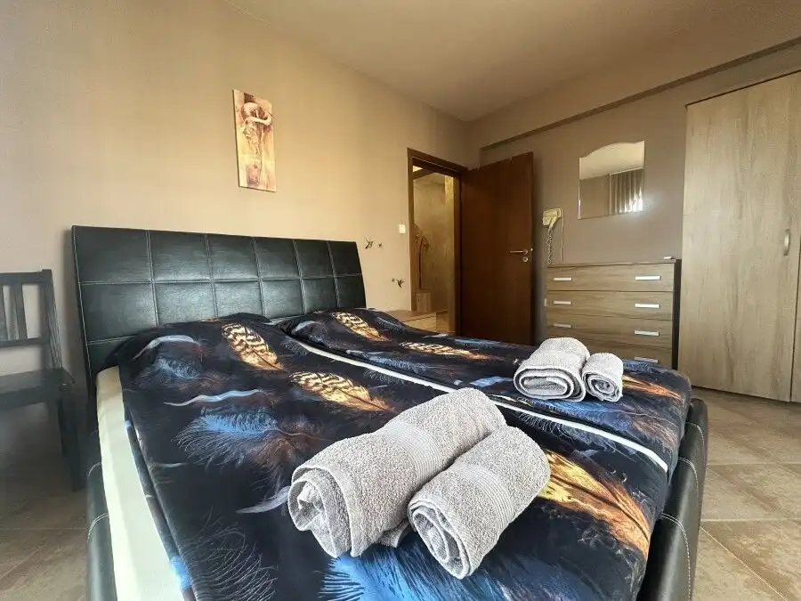 Comfortable bedroom with two beds, towels, and mountain scenery in the background.
