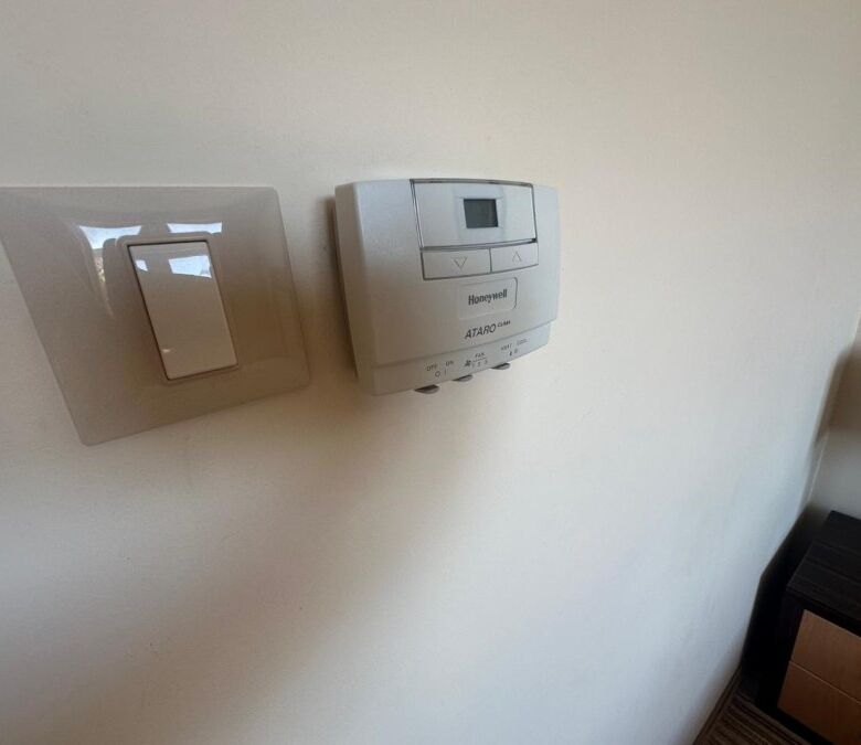 Modern thermostat and light switch on a white wall in a beachfront apartment.