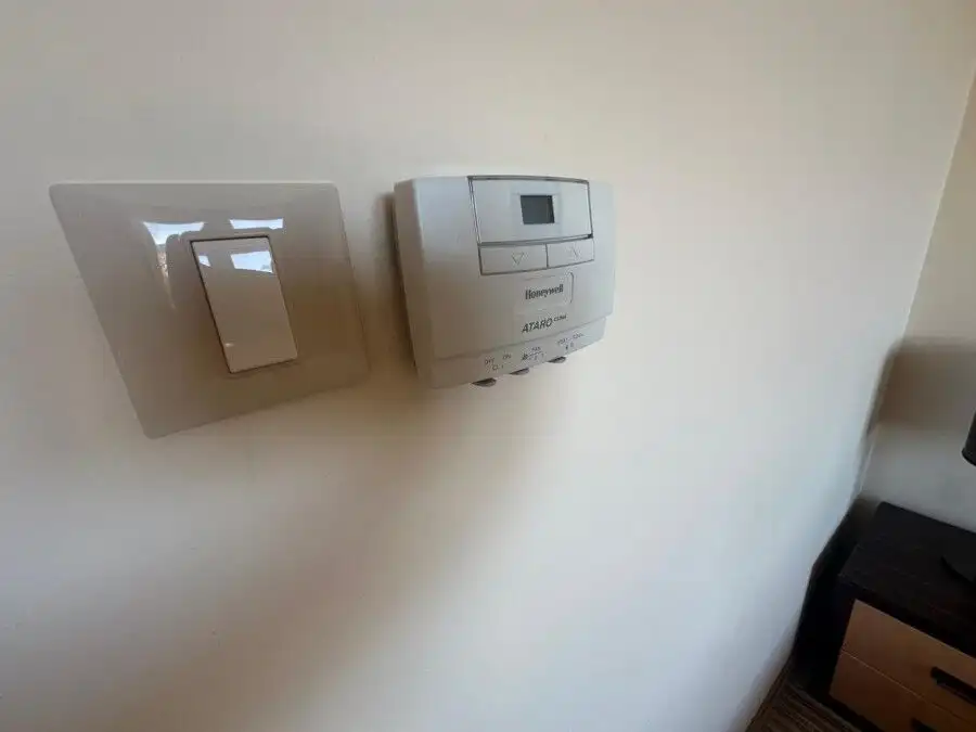 Modern thermostat and light switch on a white wall in a beachfront apartment.