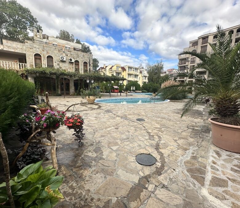 Beautiful outdoor pool area surrounded by lush greenery and stylish apartment buildings.