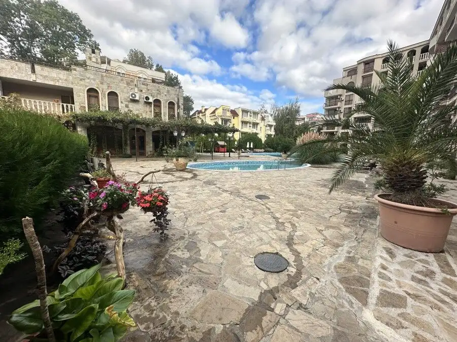Beautiful outdoor pool area surrounded by lush greenery and stylish apartment buildings.