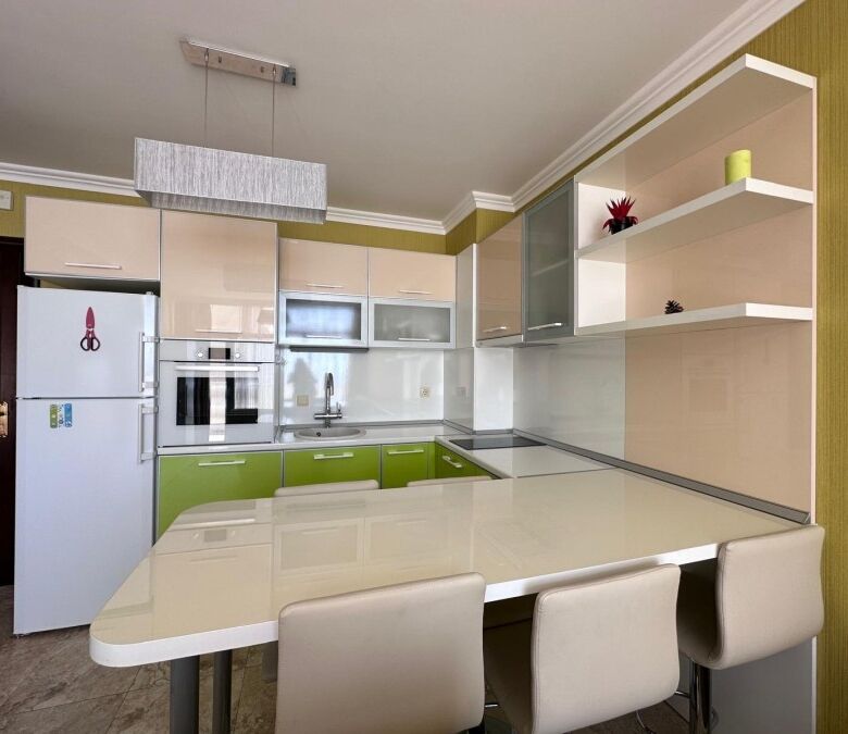 Bright, contemporary kitchen featuring green and white cabinets, a large dining table, and open shel.