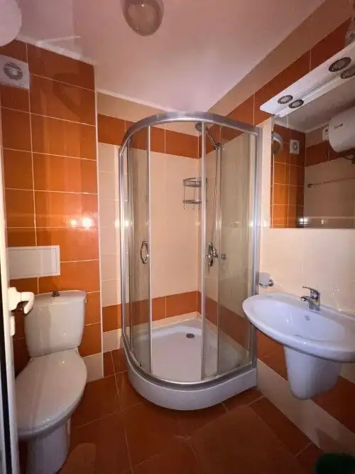 Bathroom with glass shower enclosure, toilet, and sink in a contemporary apartment.