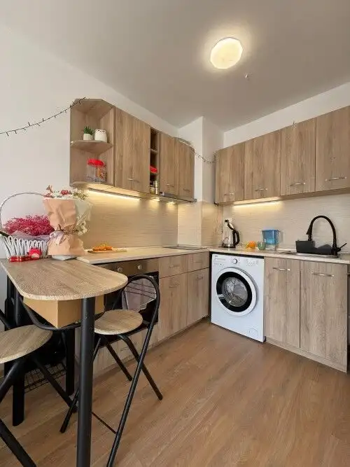 Cozy kitchen with wooden cabinets, washing machine, and dining area.