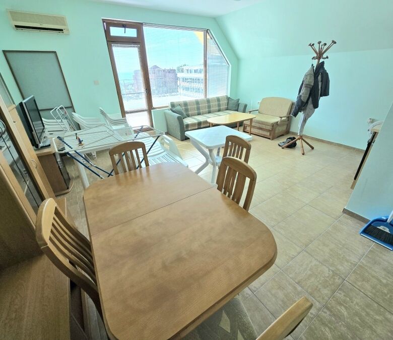 Bright living room with large windows and sea views, connected to a dining area and balcony.