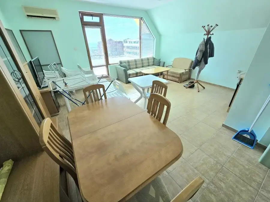 Bright living room with large windows and sea views, connected to a dining area and balcony.