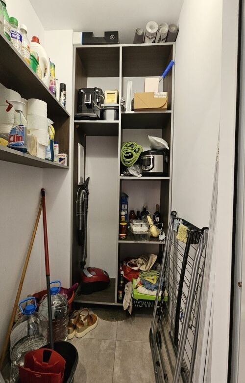 Closet with cleaning tools, bottles, and household essentials in a small utility space.