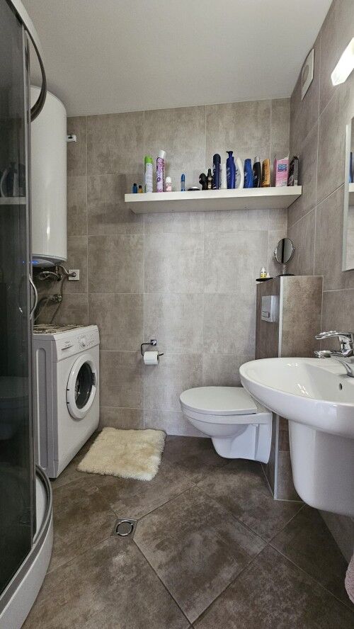 Cozy Bathroom in Modern Apartment Bright bathroom with washing machine and toiletries in a furnished apartment.