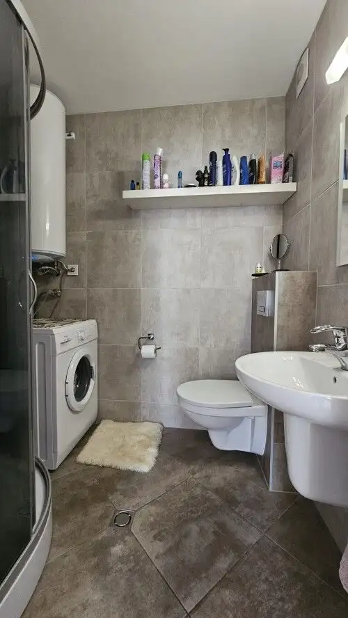 Bright bathroom with washing machine and toiletries in a furnished apartment.