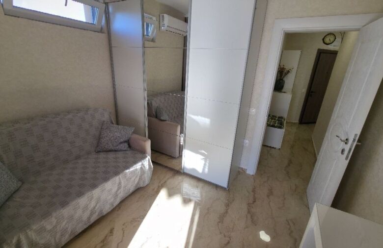 Bright living room with sofa and mirrored closet in Aphrodite Green penthouse.