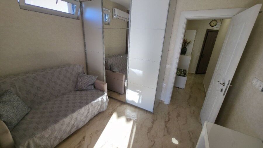 Bright living room with sofa and mirrored closet in Aphrodite Green penthouse.