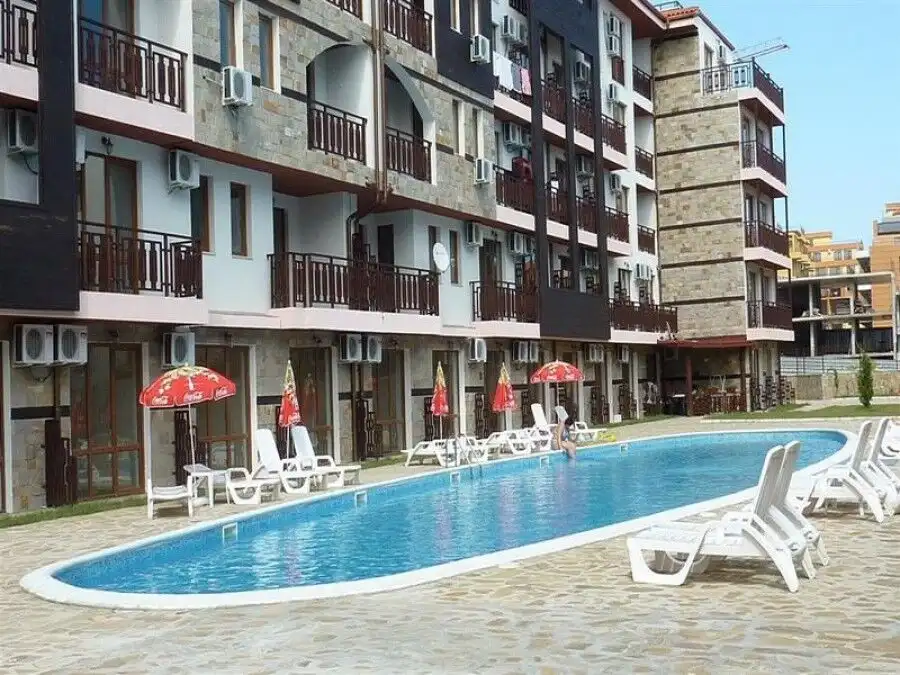 Stylish residential complex featuring a swimming pool, sun loungers, and shaded seating areas.