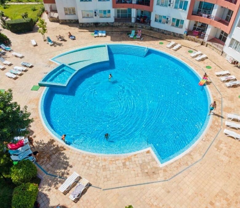 Pool area at Riviera Fort in Ravda with sun loungers and clear blue water.