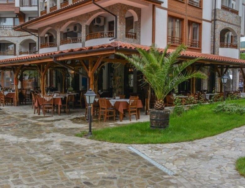 Outdoor dining area with wooden tables and lush greenery in Sveti Vlas, near Olymp. Perfect for rela.