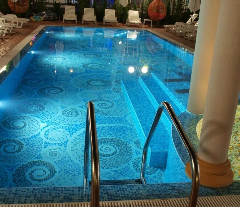 Luxurious swimming pool featuring vibrant mosaic tiles and surrounding sun loungers for relaxation.