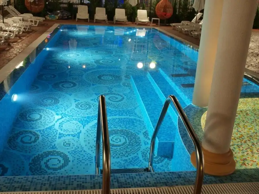 Luxurious swimming pool featuring vibrant mosaic tiles and surrounding sun loungers for relaxation.