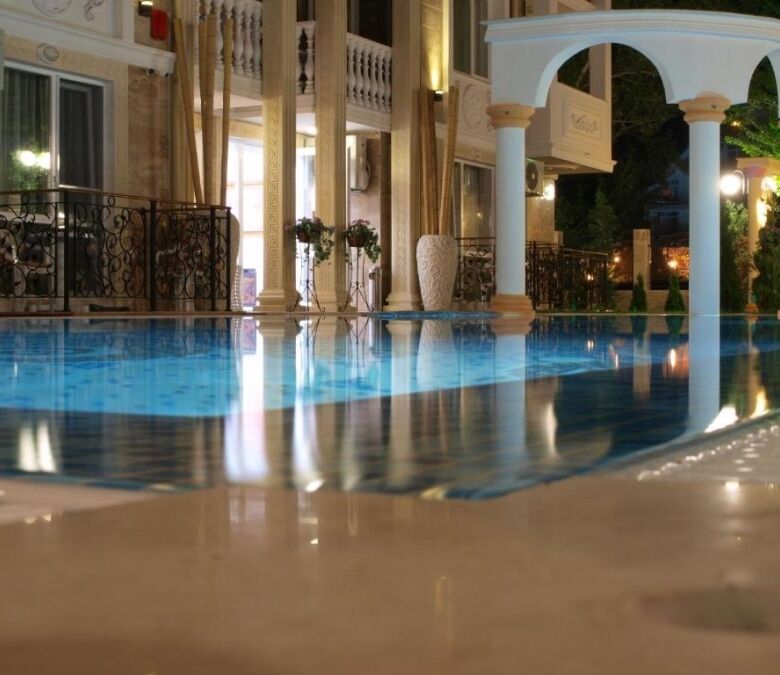 Indoor pool with ornate design, large windows, and stylish furnishings in a top-floor apartment.