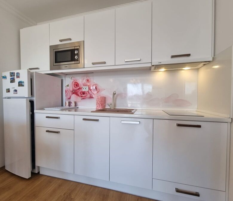 Bright kitchen with white cabinetry, microwave, and refrigerator in a contemporary apartment.