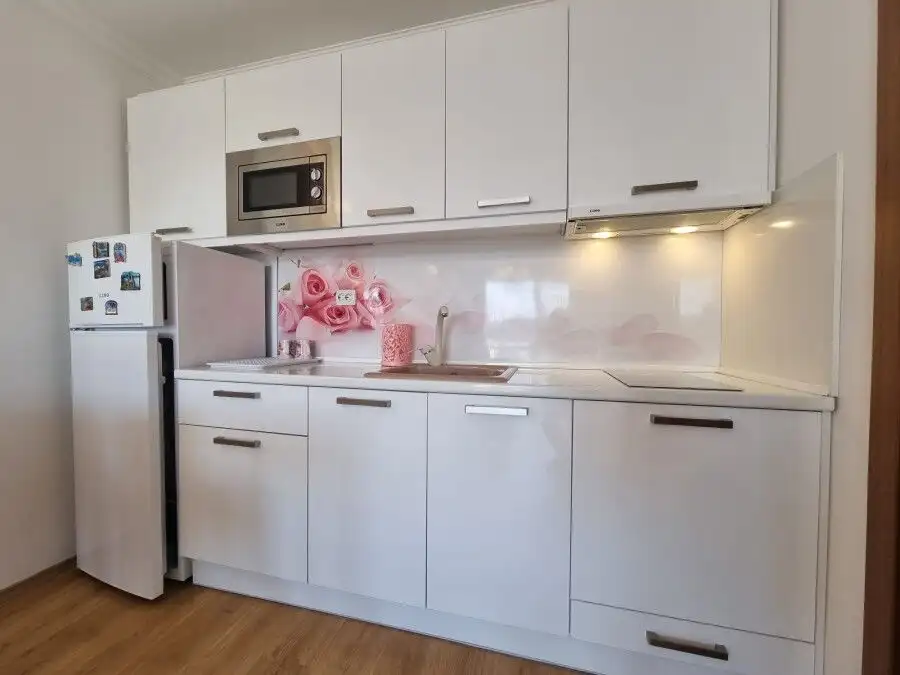 Bright kitchen with white cabinetry, microwave, and refrigerator in a contemporary apartment.