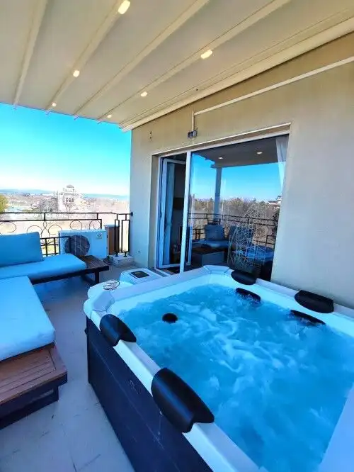 Balcony with Jacuzzi and seating area overlooking scenic city views in Pomorie Residence.