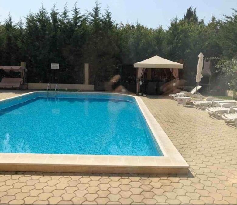 Pool with sun loungers and shaded seating area at Pomorie Residence.