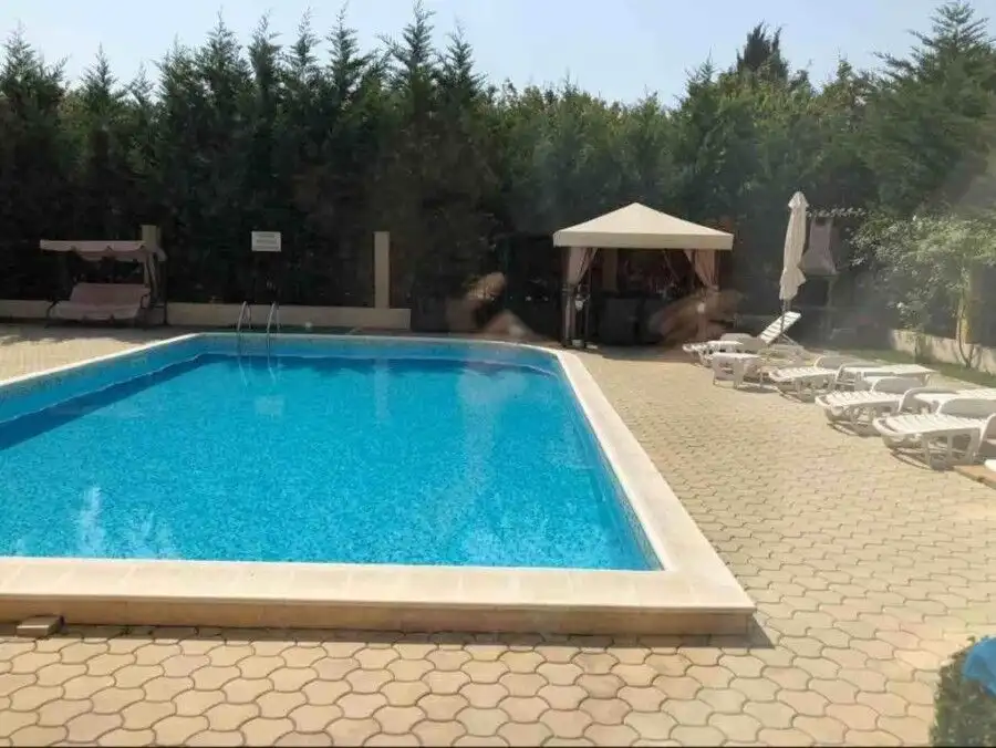 Pool with sun loungers and shaded seating area at Pomorie Residence.