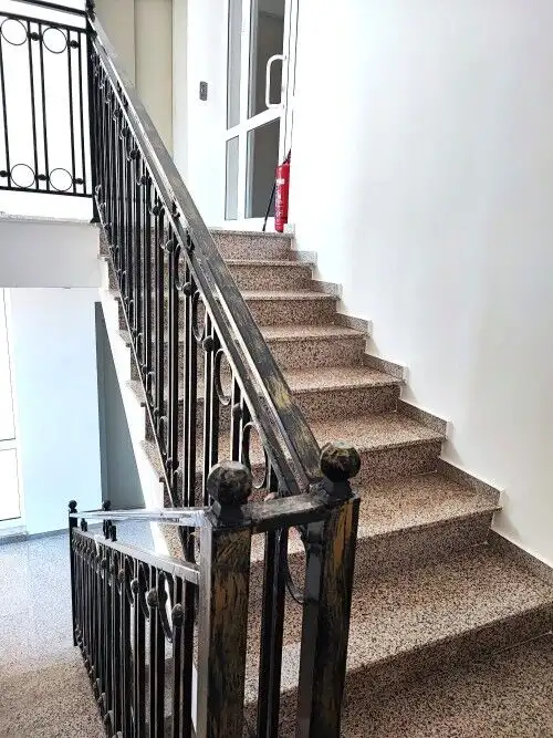Staircase with black wrought iron railing leading to an upper floor in a modern apartment building.
