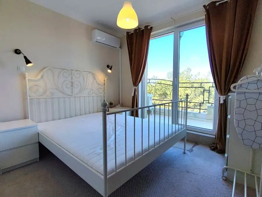Cozy bedroom with large window, balcony access, and scenic views in Pomorie Residence.