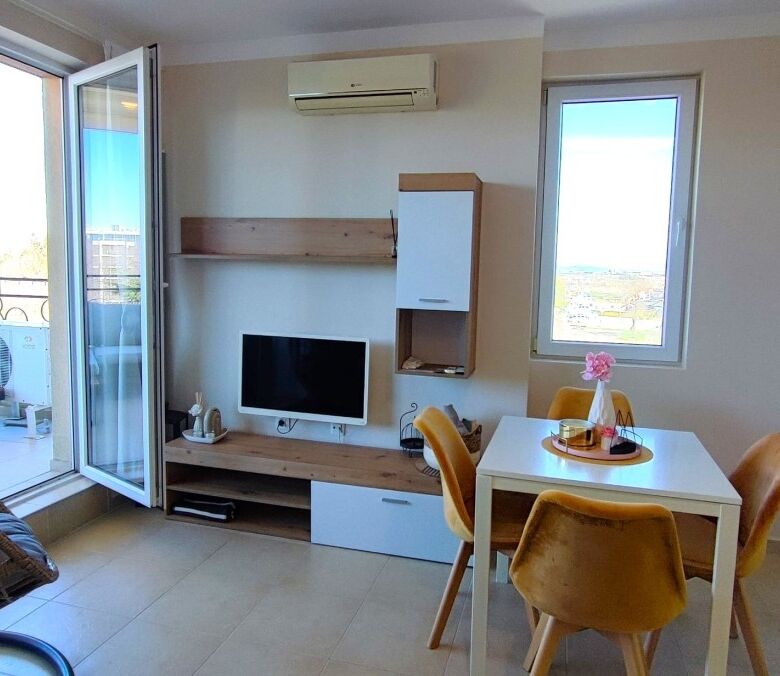 Interior view of a 1-bedroom apartment with a balcony, modern furniture, and a small dining area.