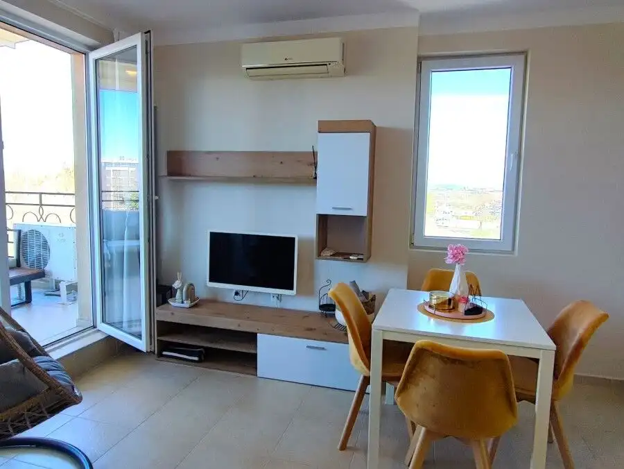 Interior view of a 1-bedroom apartment with a balcony, modern furniture, and a small dining area.