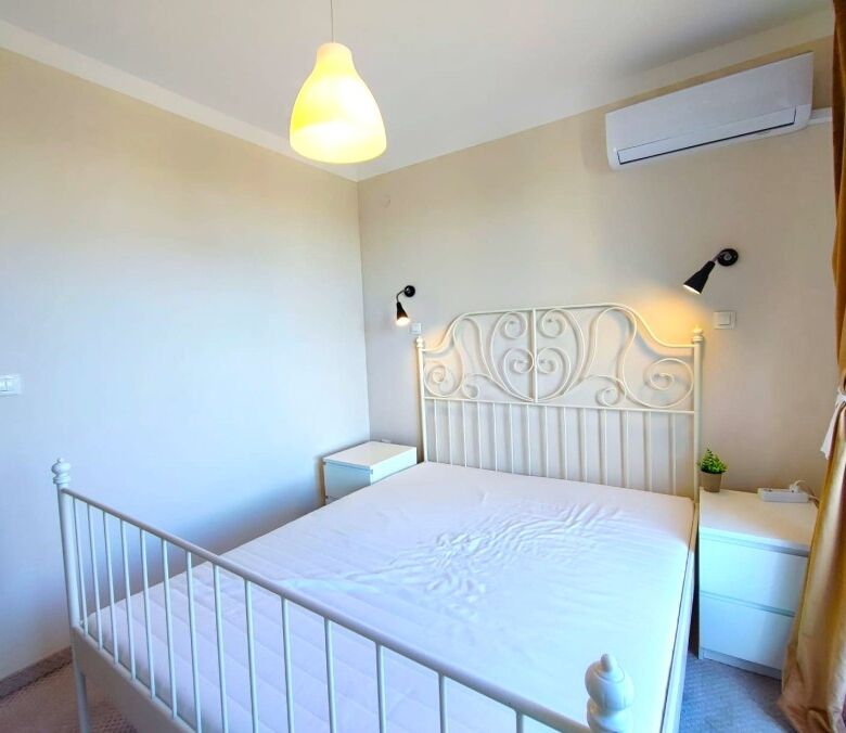 Bright bedroom with white bed and elegant headboard in Pomorie apartment.