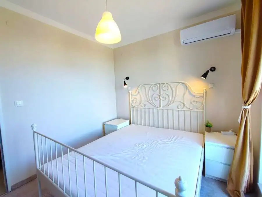 Bright bedroom with white bed and elegant headboard in Pomorie apartment.